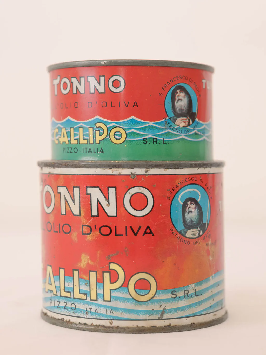 Two stacked tins of tuna in olive oil with worn printed labels