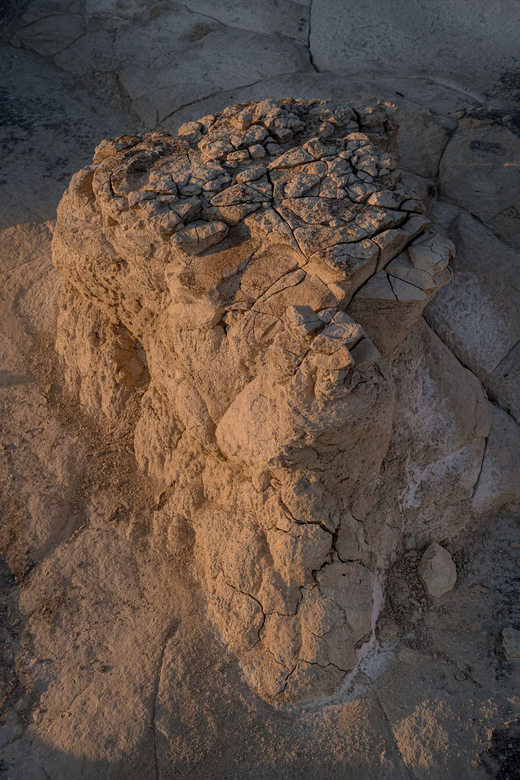 Cracked clay boulder resting on dry ground, its top split by the sun