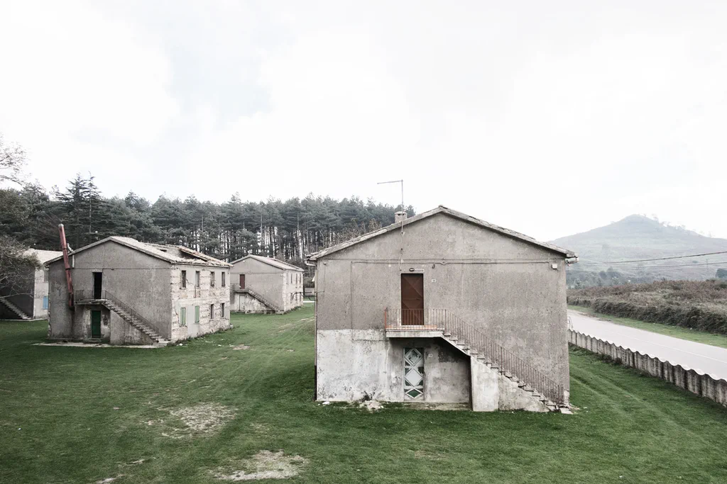 Abandoned houses on a green slope, an external staircase on the nearest one