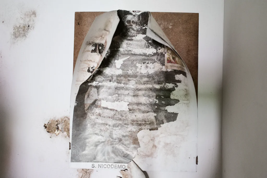 Torn devotional print on a damp wall