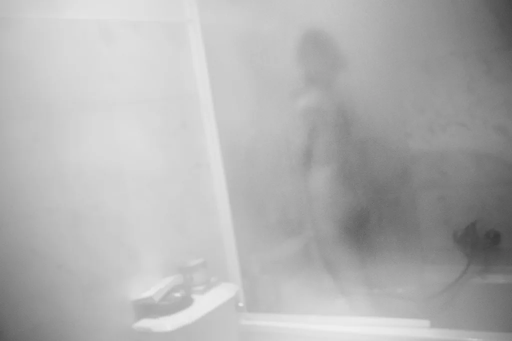 Blurred figure behind frosted glass, a pair of shoes on the floor