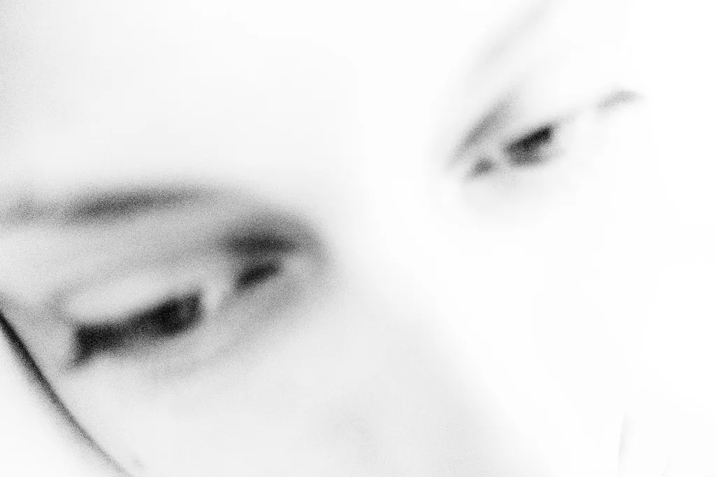 Face very close to the lens, eyes lowered, out of focus