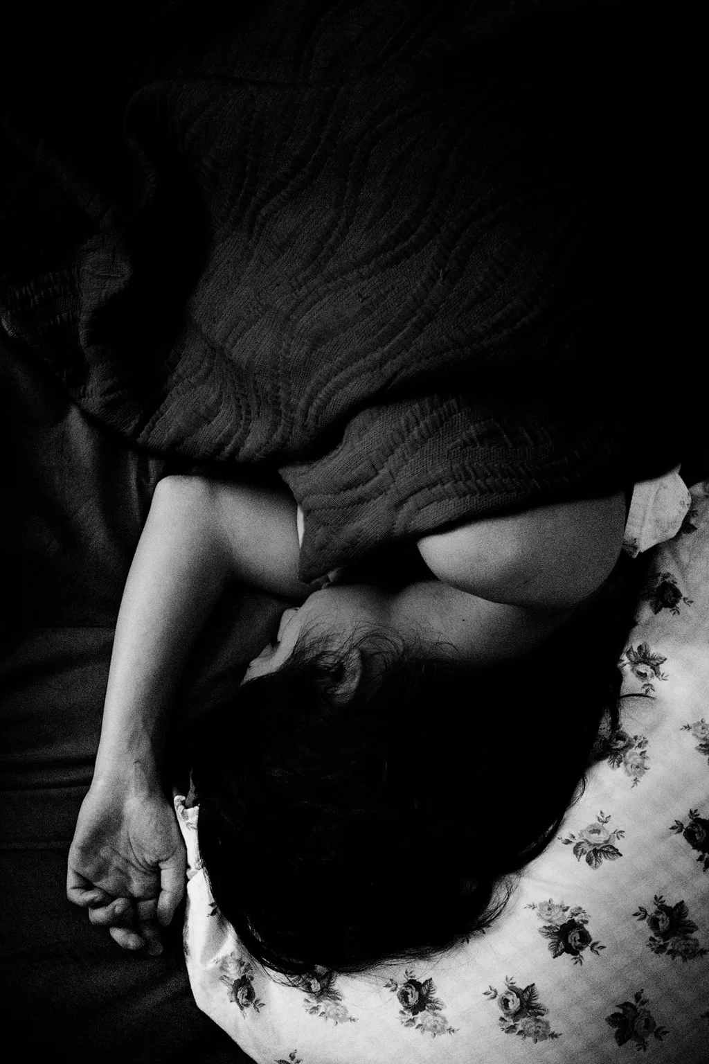 Person curled up asleep on a patterned bedspread
