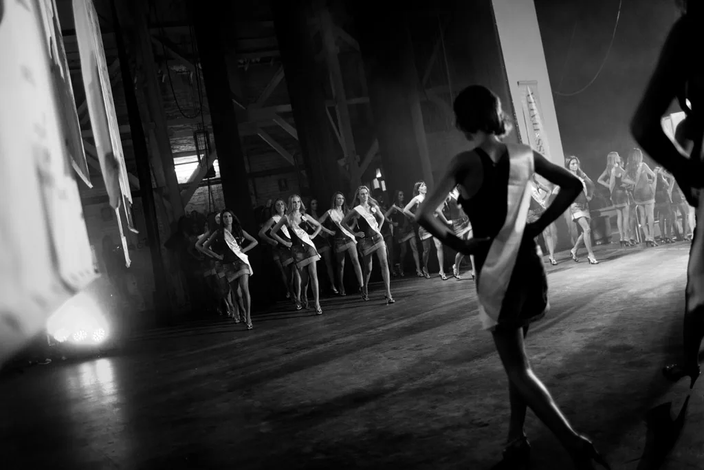 Rehearsal on a dark stage, a contestant walking towards the others