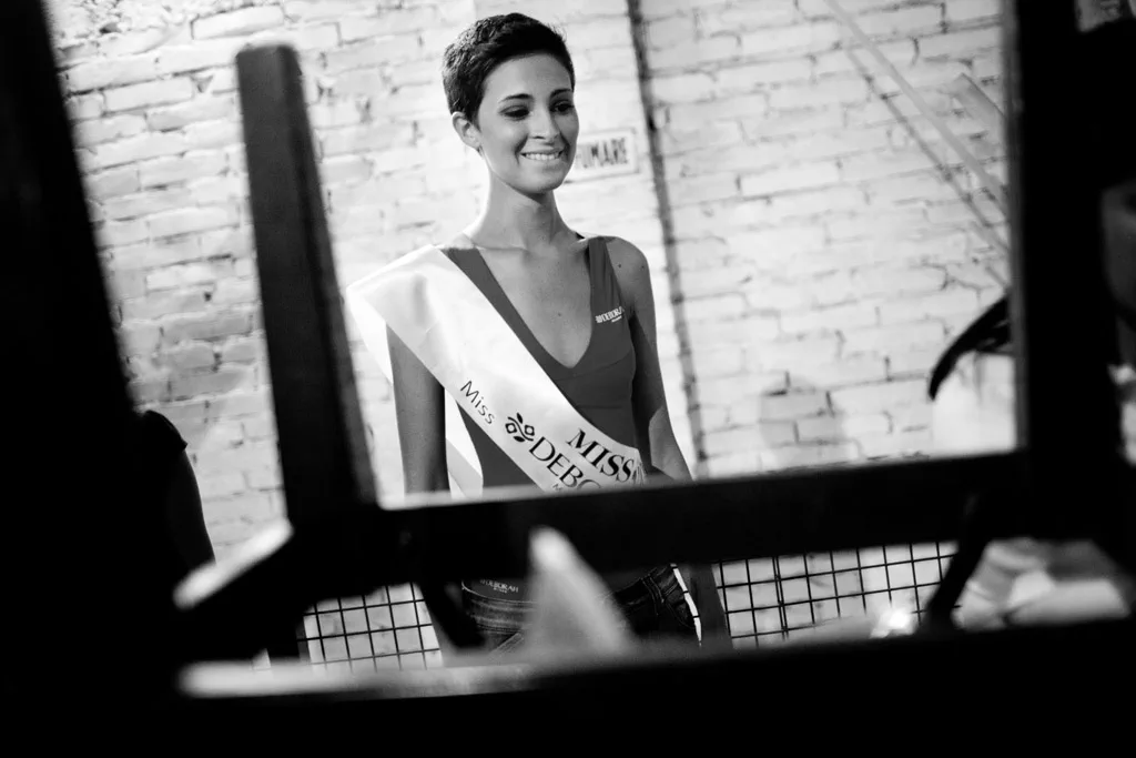 Contestant reflected in a mirror leaning against a brick wall