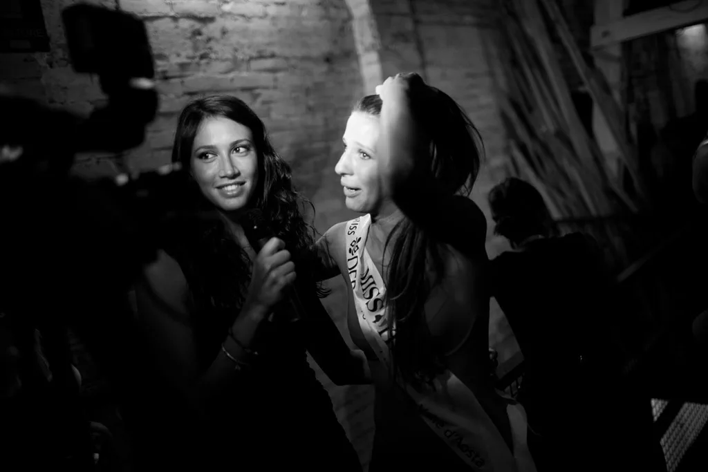Two contestants talking in the half-light backstage