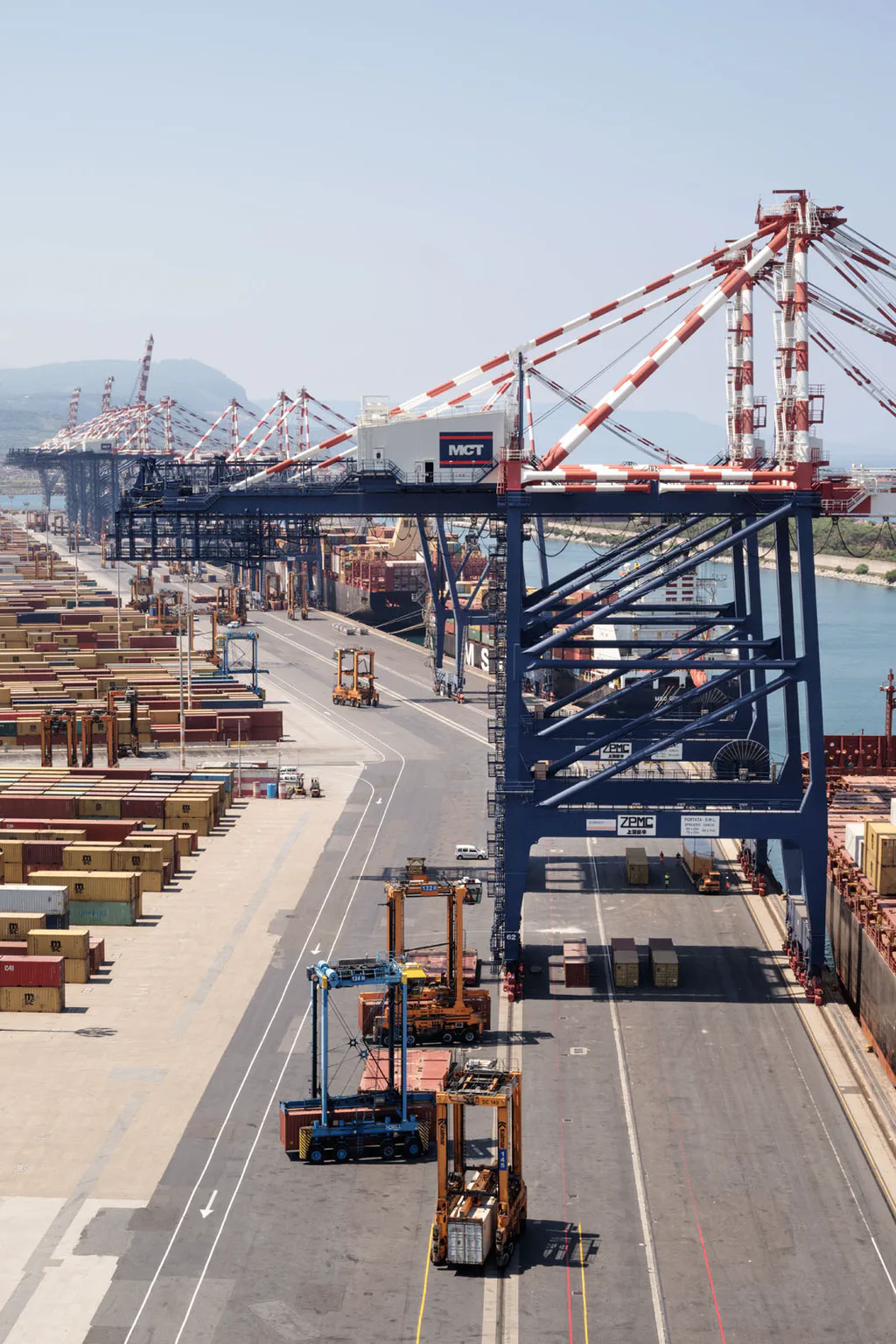 Straddle carrier moving along the quay between stacks of containers