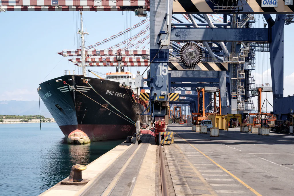 Bow of a container ship moored at the quay beneath a crane