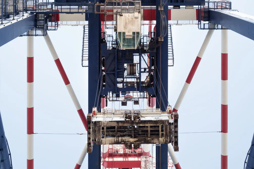 Crane spreader hanging between the legs of a gantry, seen from below