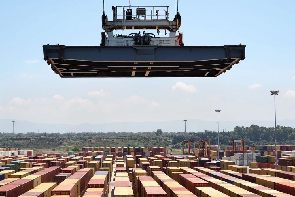Crane spreader suspended in the air above the container yard