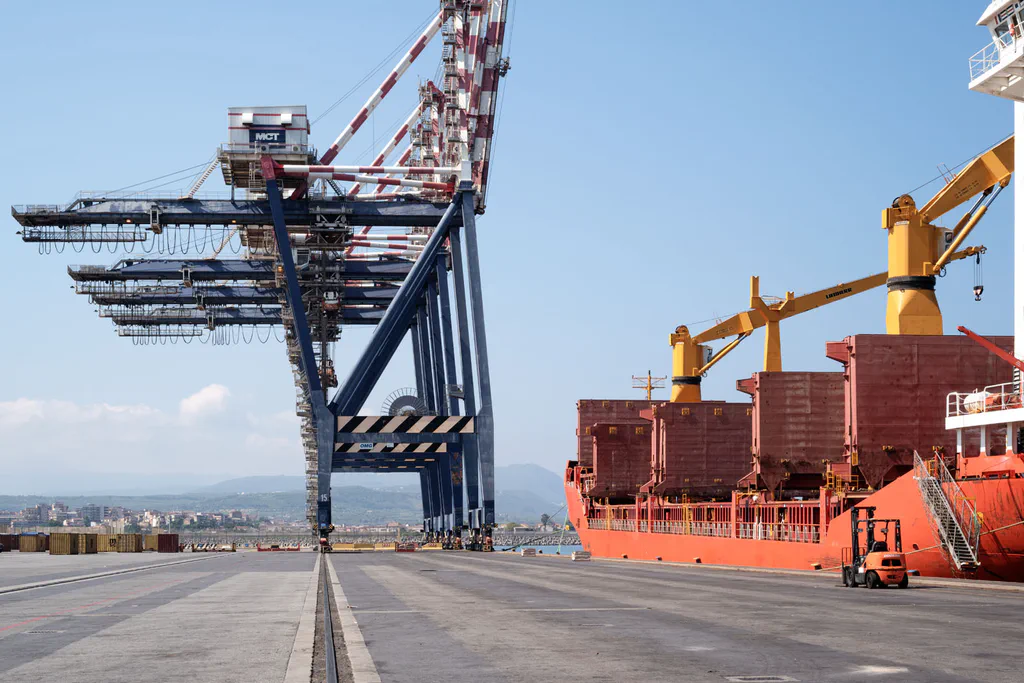 Gantry crane beside a red ship at the quay