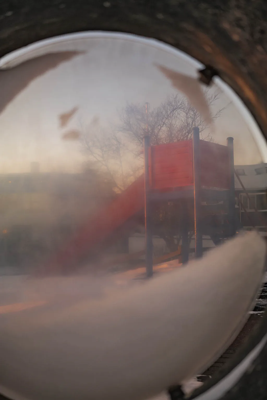 Convex traffic mirror clouded with frost, a red sign reflected in it