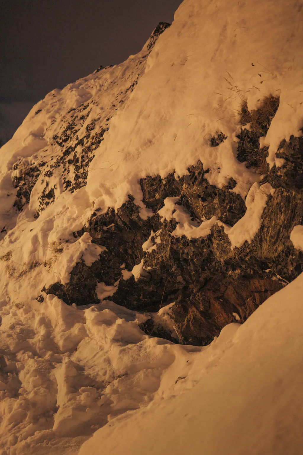 Snow-covered slope with dark rock breaking through