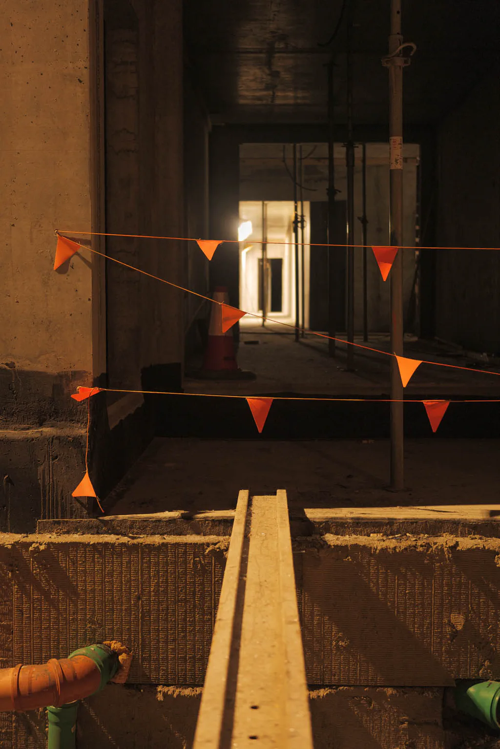 Building site at night, orange bunting stretched across a dark passage