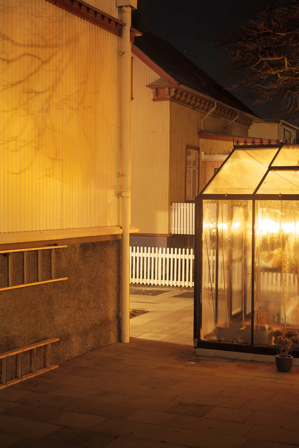 Lit greenhouse beside a house at night