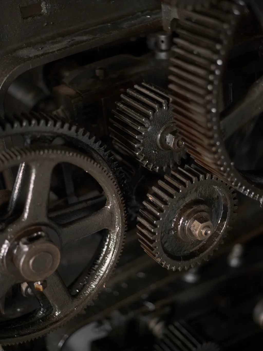 Interlocking cogwheels of an industrial machine, dark with oil