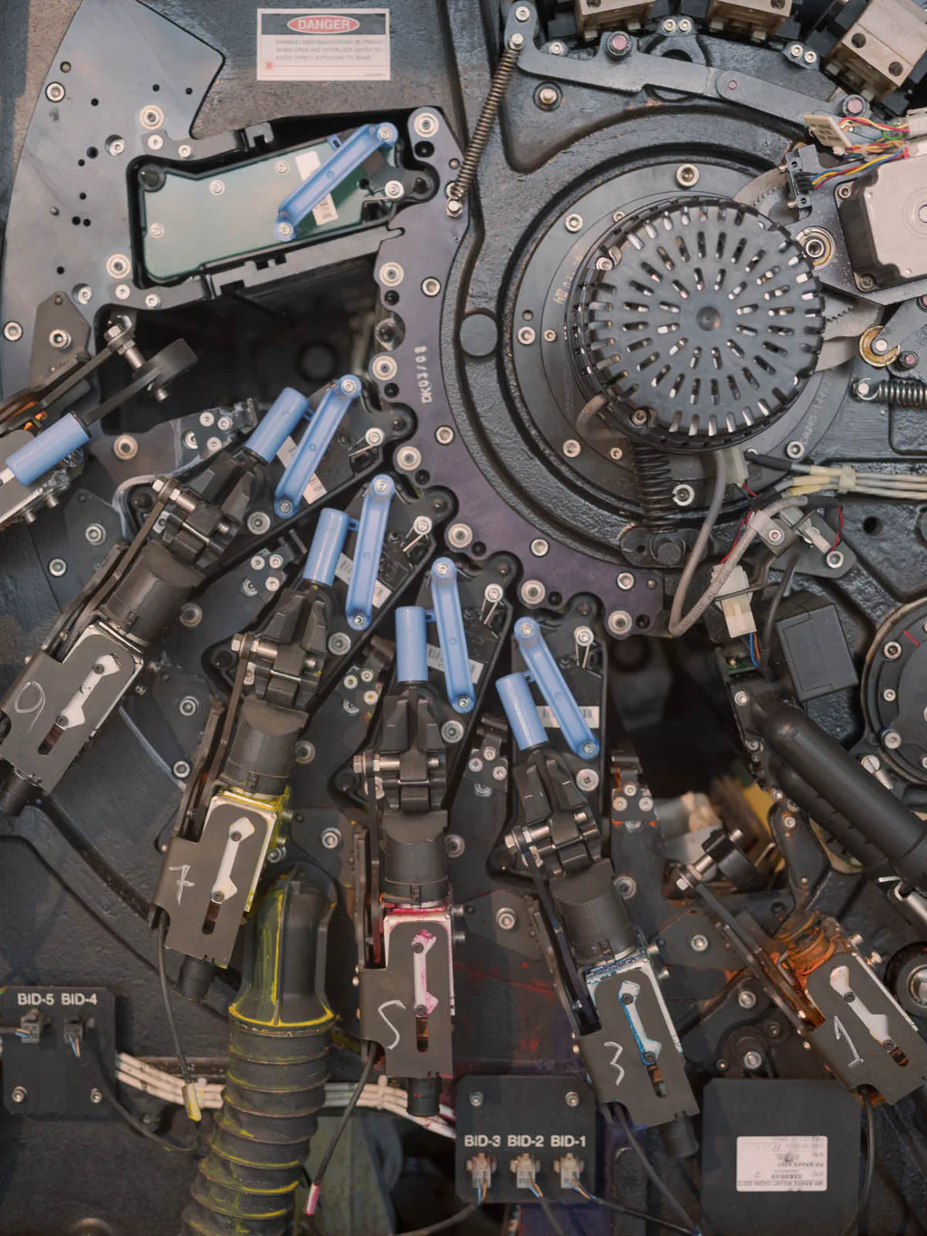 Panel of an industrial machine crowded with valves, cables and coloured switches