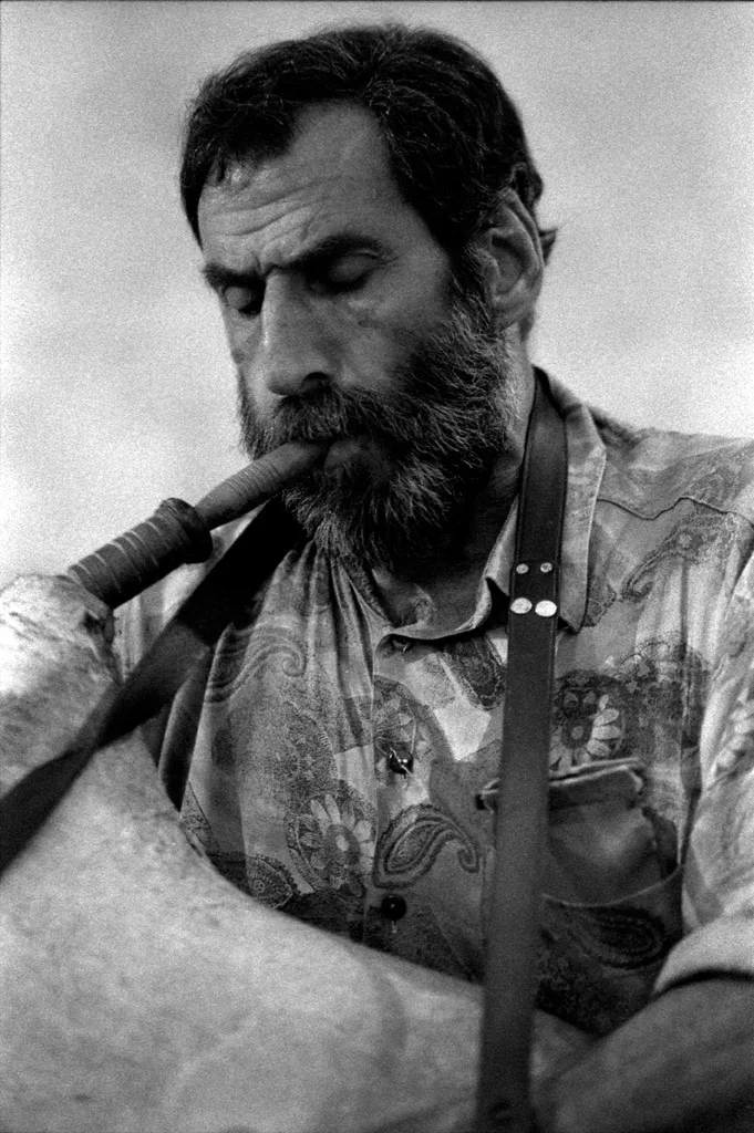Man with a beard blowing into a bagpipe