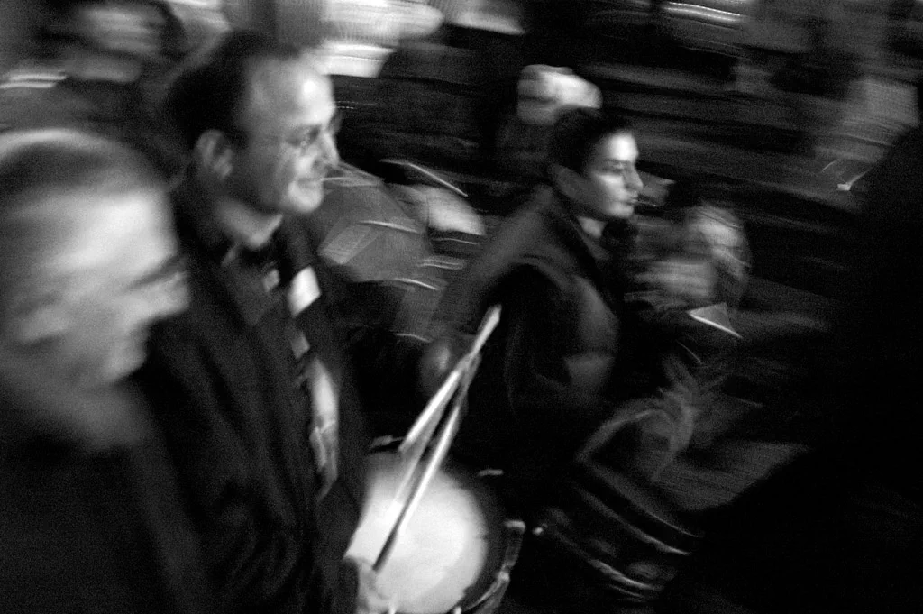 Drummers moving through a street, the picture blurred by their motion