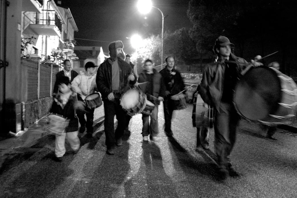 Drummers walking down a street under streetlights