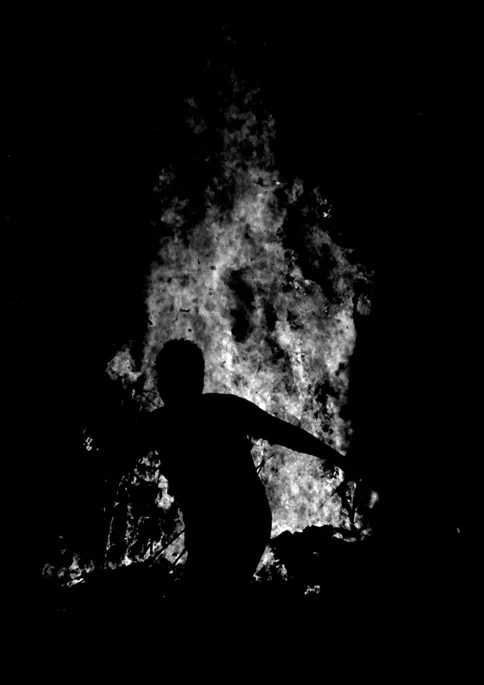 A figure beside a bonfire in the dark