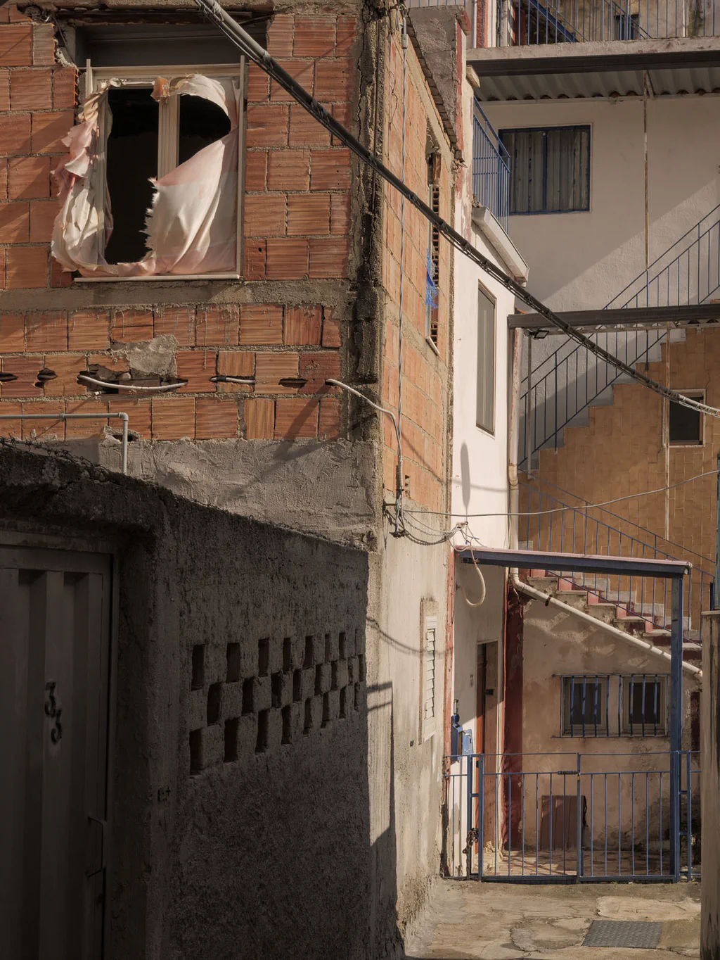 Narrow alley between old houses, a broken window and tangled cables overhead