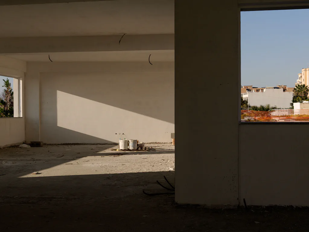 Empty concrete interior open on one side to the sky and the rooftops
