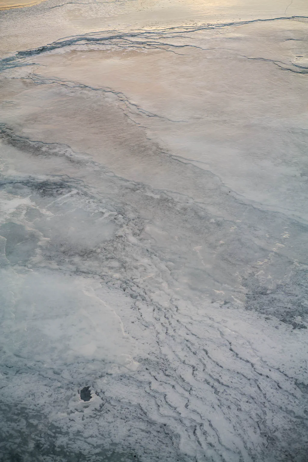 Thin ice breaking over pale shallow water