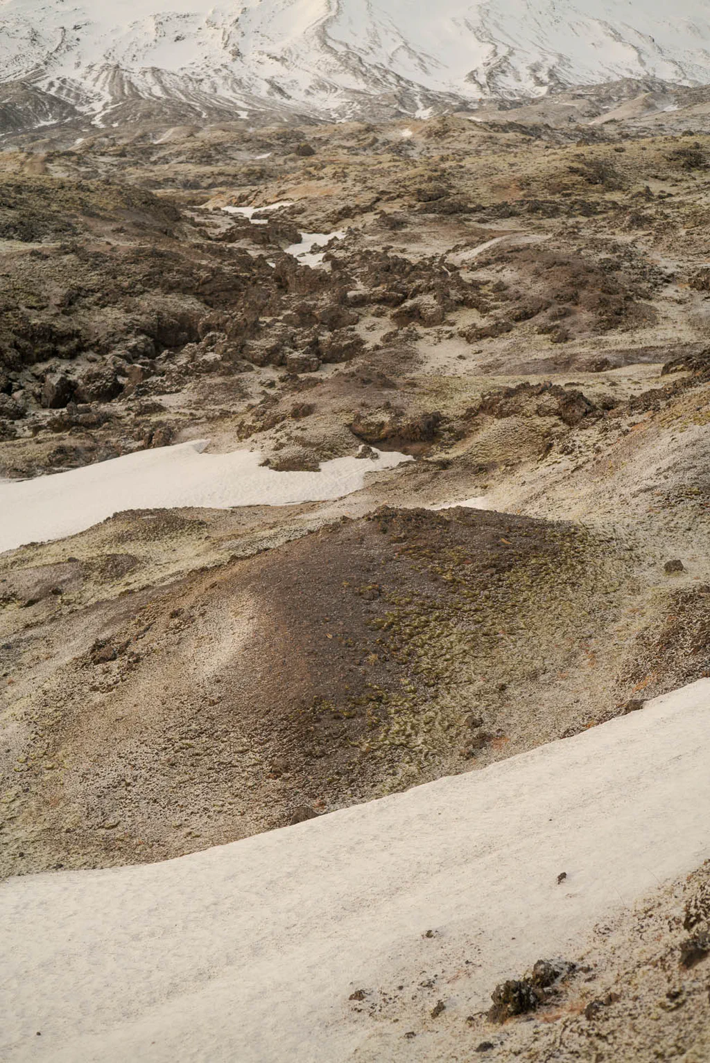 Volcanic hills streaked with snow above a wide pale slope