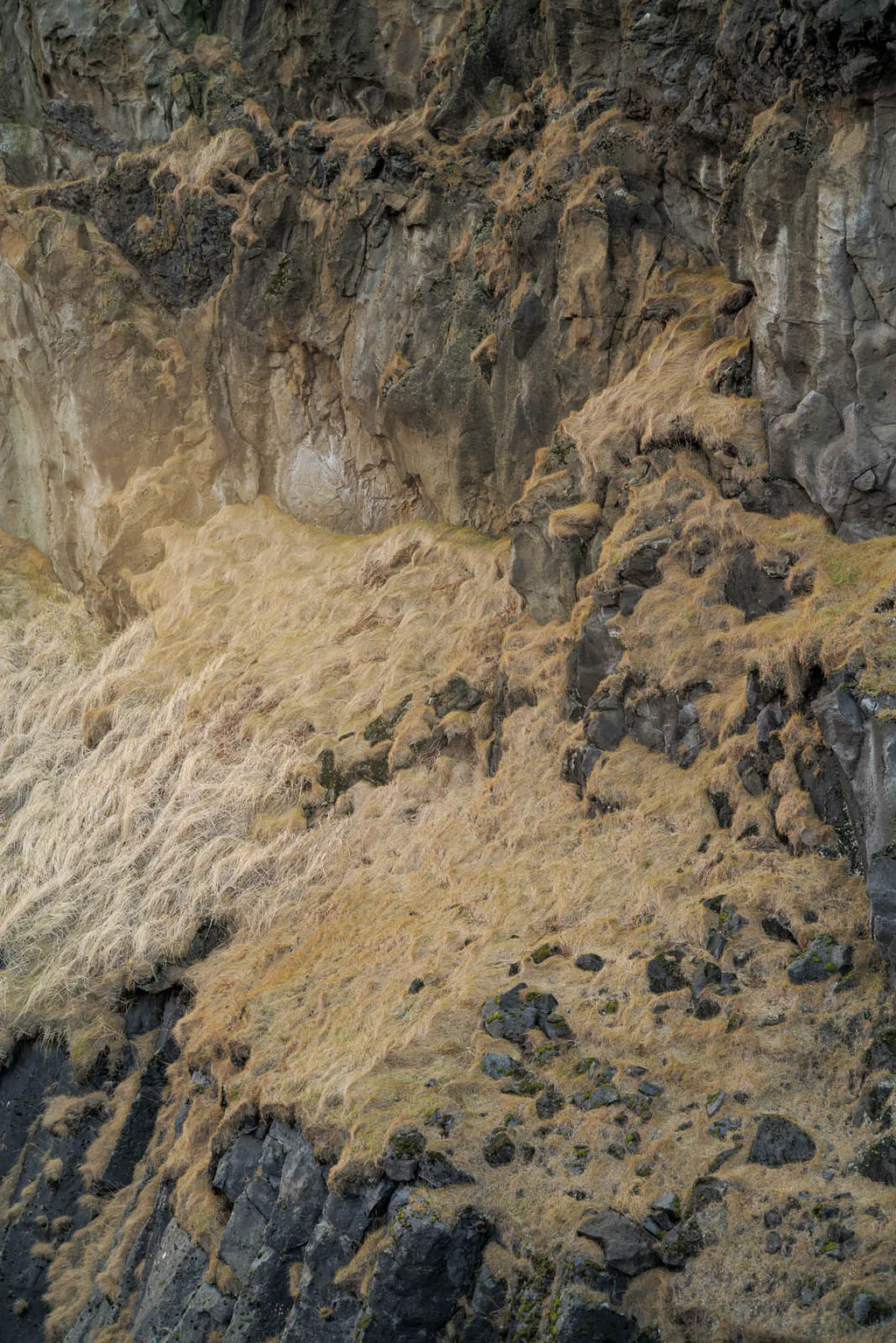 Rock face of layered basalt with ochre mineral deposits