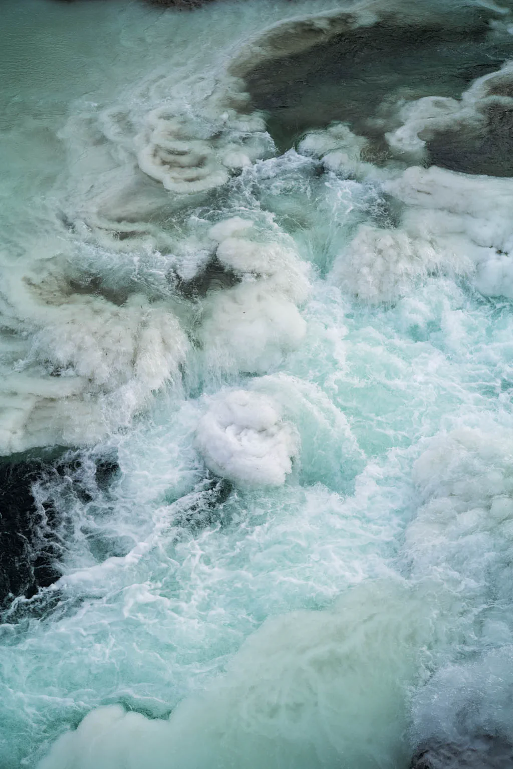 Turquoise water churning white around blocks of ice