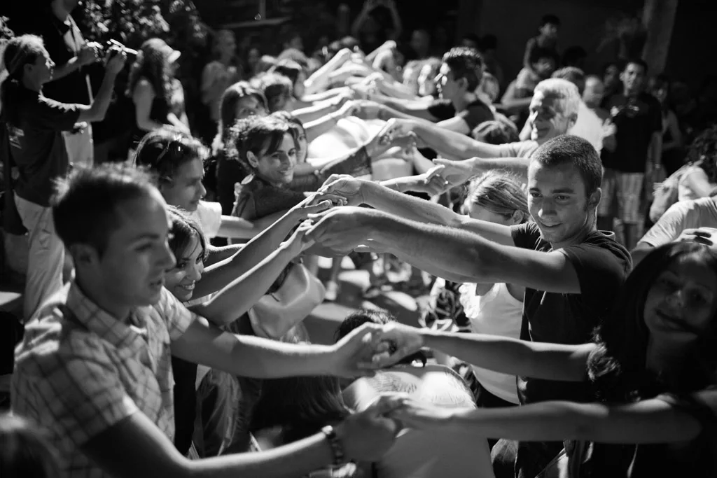 Crowd reaching out with hands and tambourines, faces lit from the front