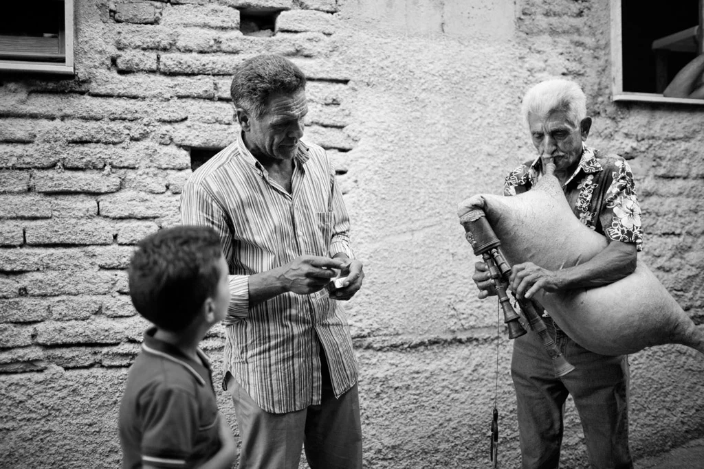 Three generations with instruments in front of a brick wall, a child watching