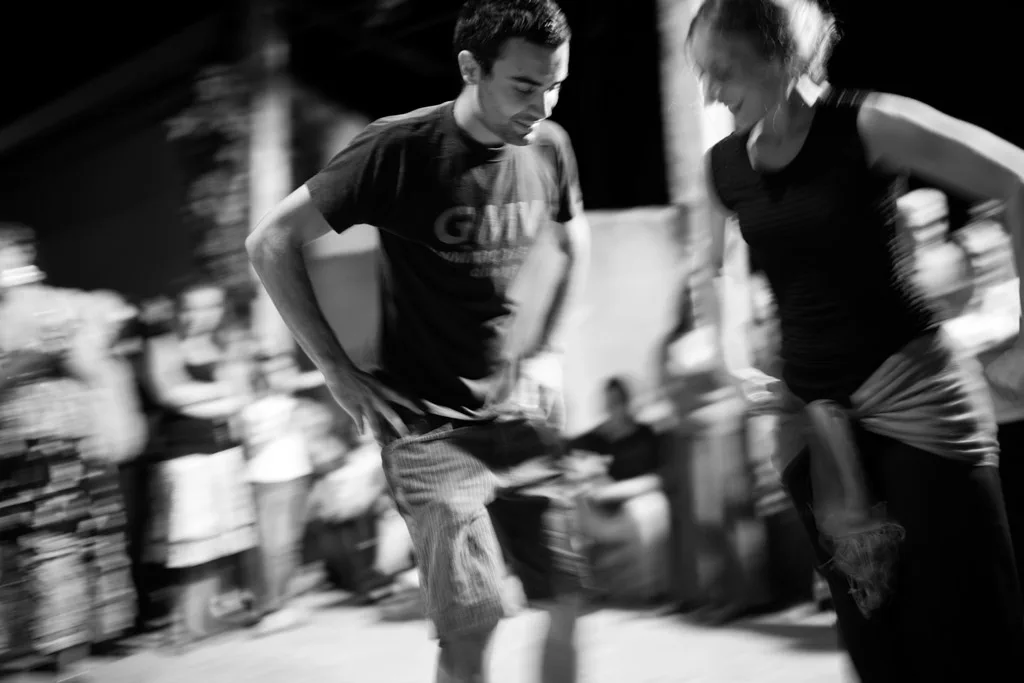Couple dancing outdoors at night, a crowd behind them