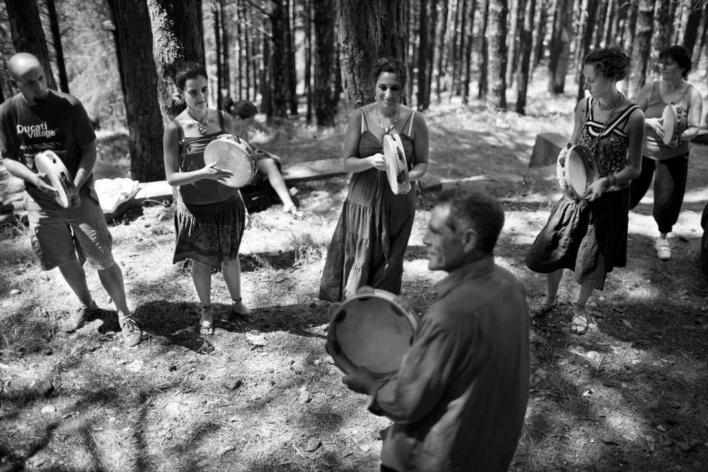 Group playing frame drums in a pine wood