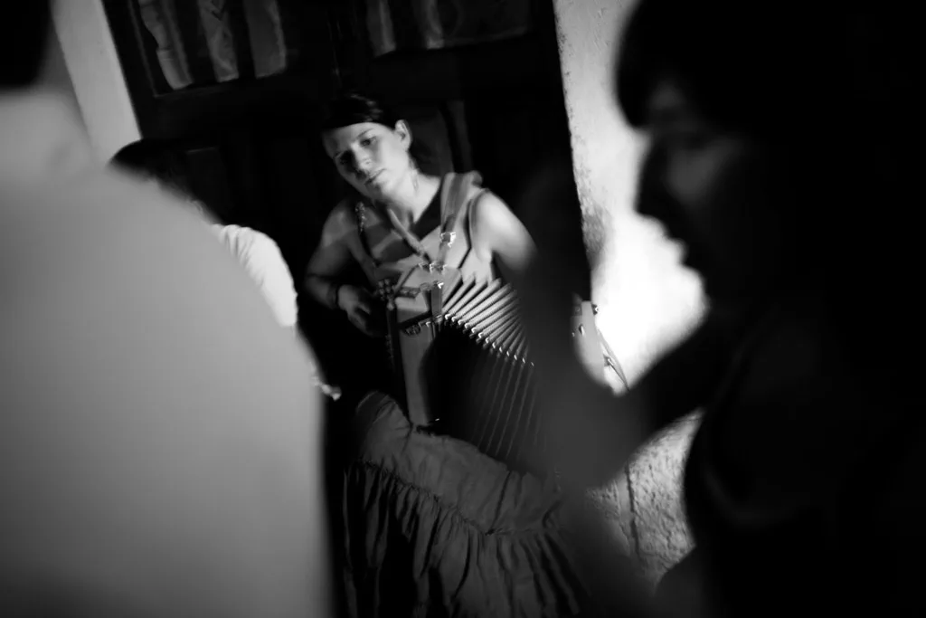 Woman dancing among figures in the dark, seen between two silhouettes