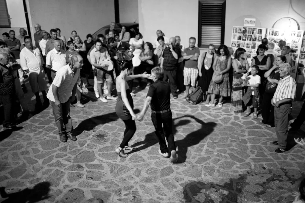 Dancers on a paved square ringed by a standing crowd