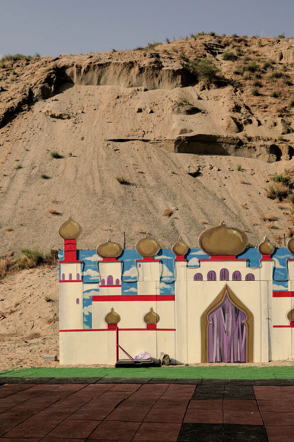 Painted fairground castle standing at the foot of an eroded clay slope