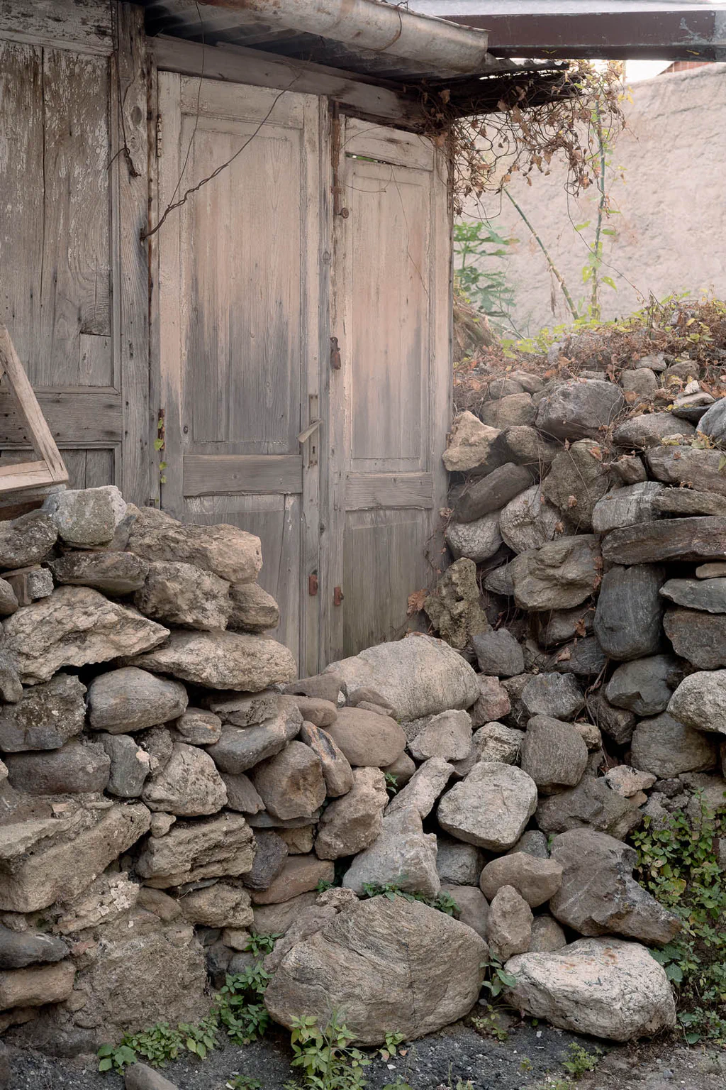 Old wooden door behind a heap of stones cleared from the ground