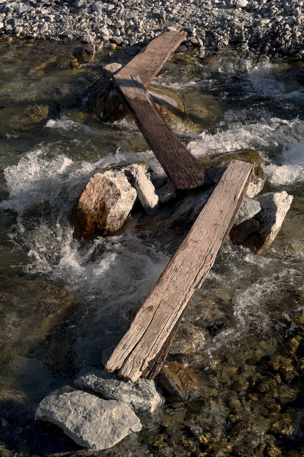 Planks and boulders caught in the current of a shallow river