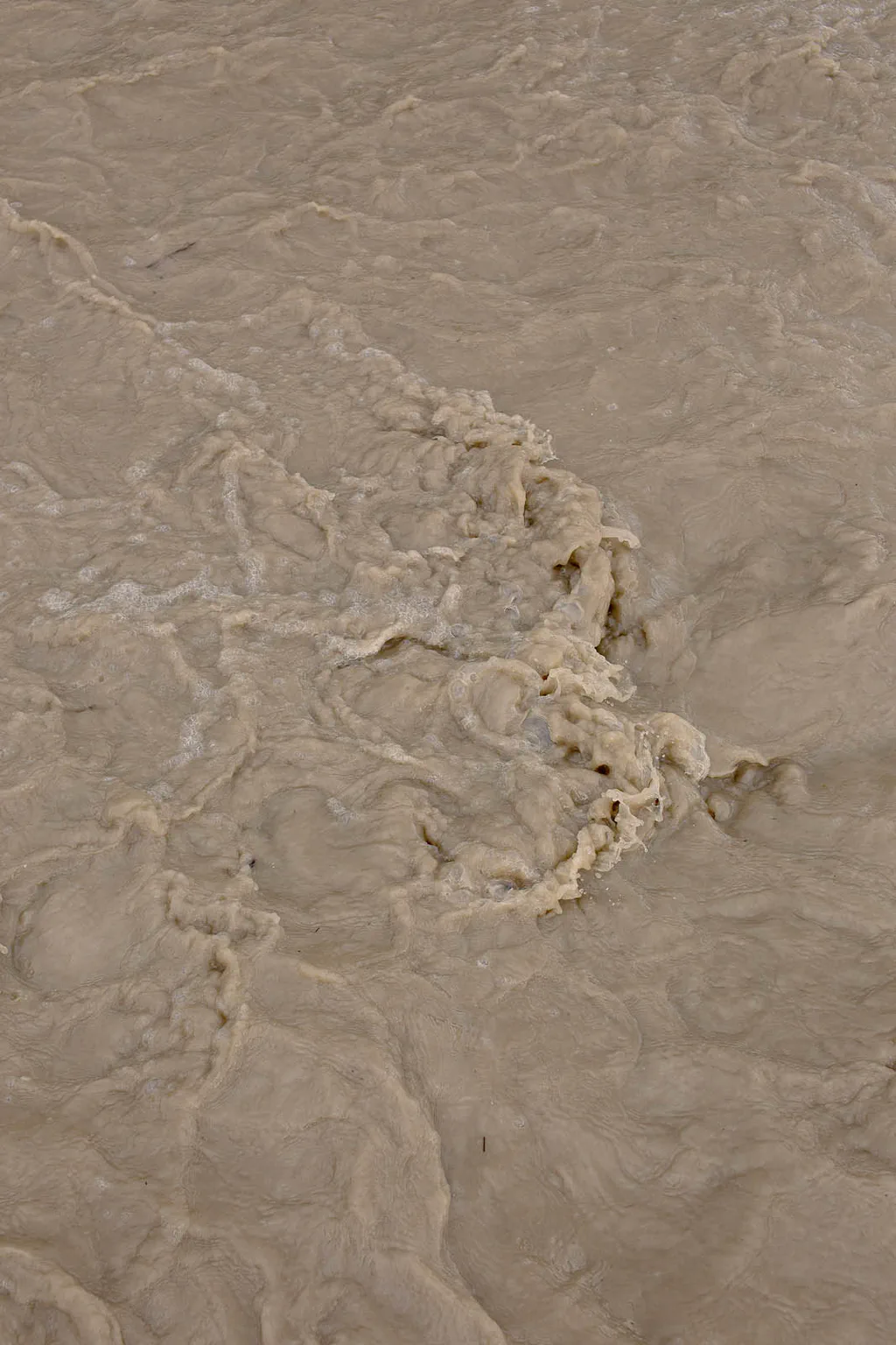 Pale mud swirling in shallow water